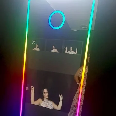 Guests enjoying fun moments at a Mirror Photobooth with interactive touch screen and colorful props.